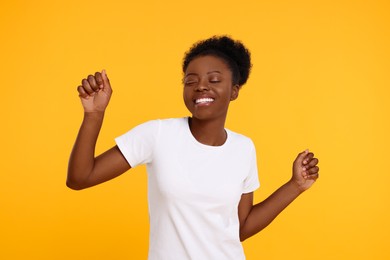 Portrait of happy young woman on orange background