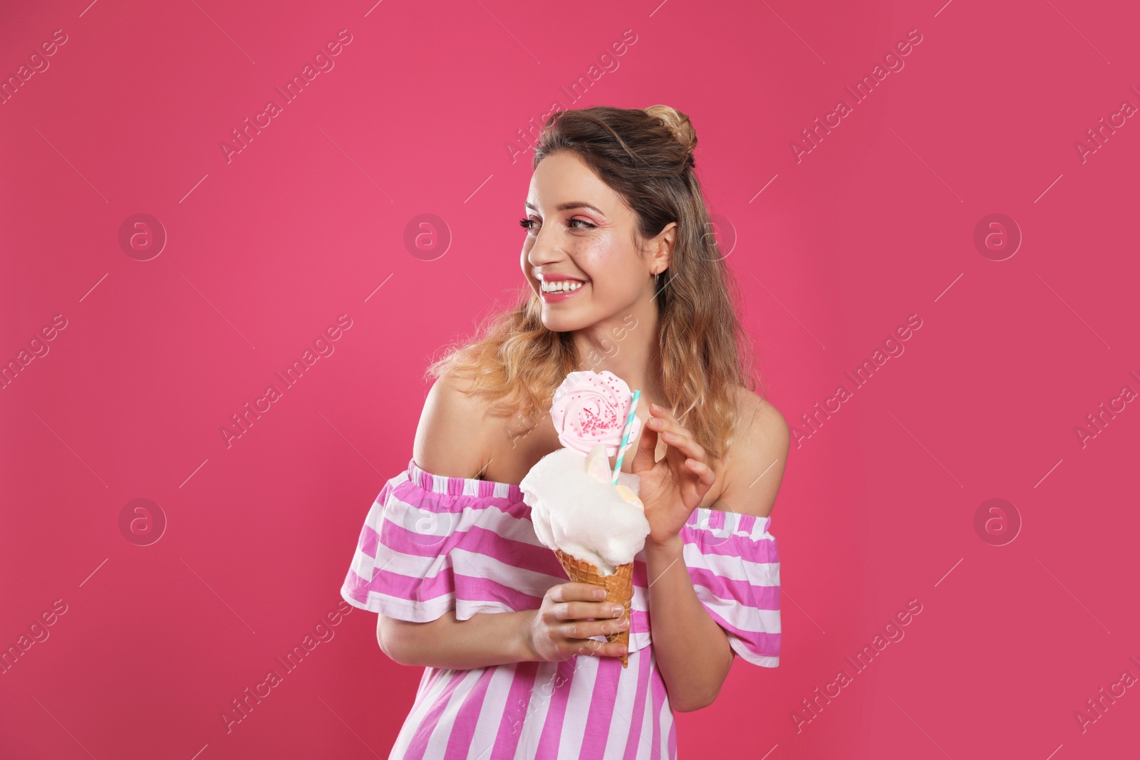 Photo of Portrait of young woman holding cotton candy dessert on pink background