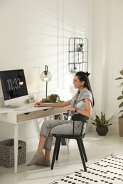 Photo of Young woman working at table in light room. Home office