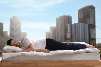 Image of Man sleeping on bed and beautiful view of cityscape on background. Good sleep despite of urban noise