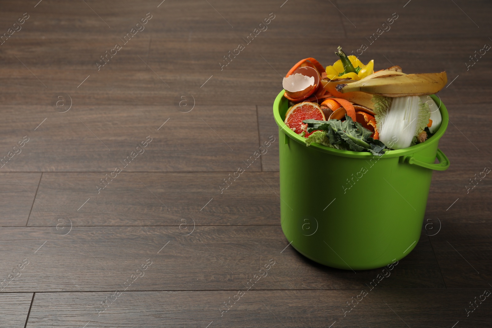Photo of Trash bin with natural garbage on wooden background, space for text. Composting of organic waste