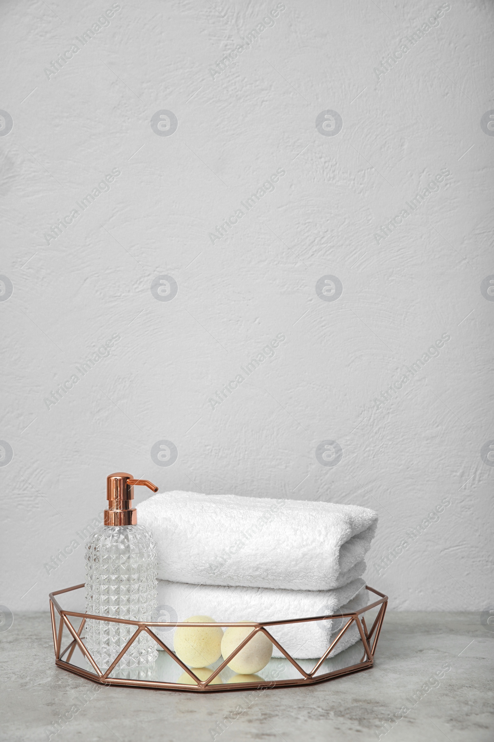 Photo of Tray with towels and toiletries on table against grey background