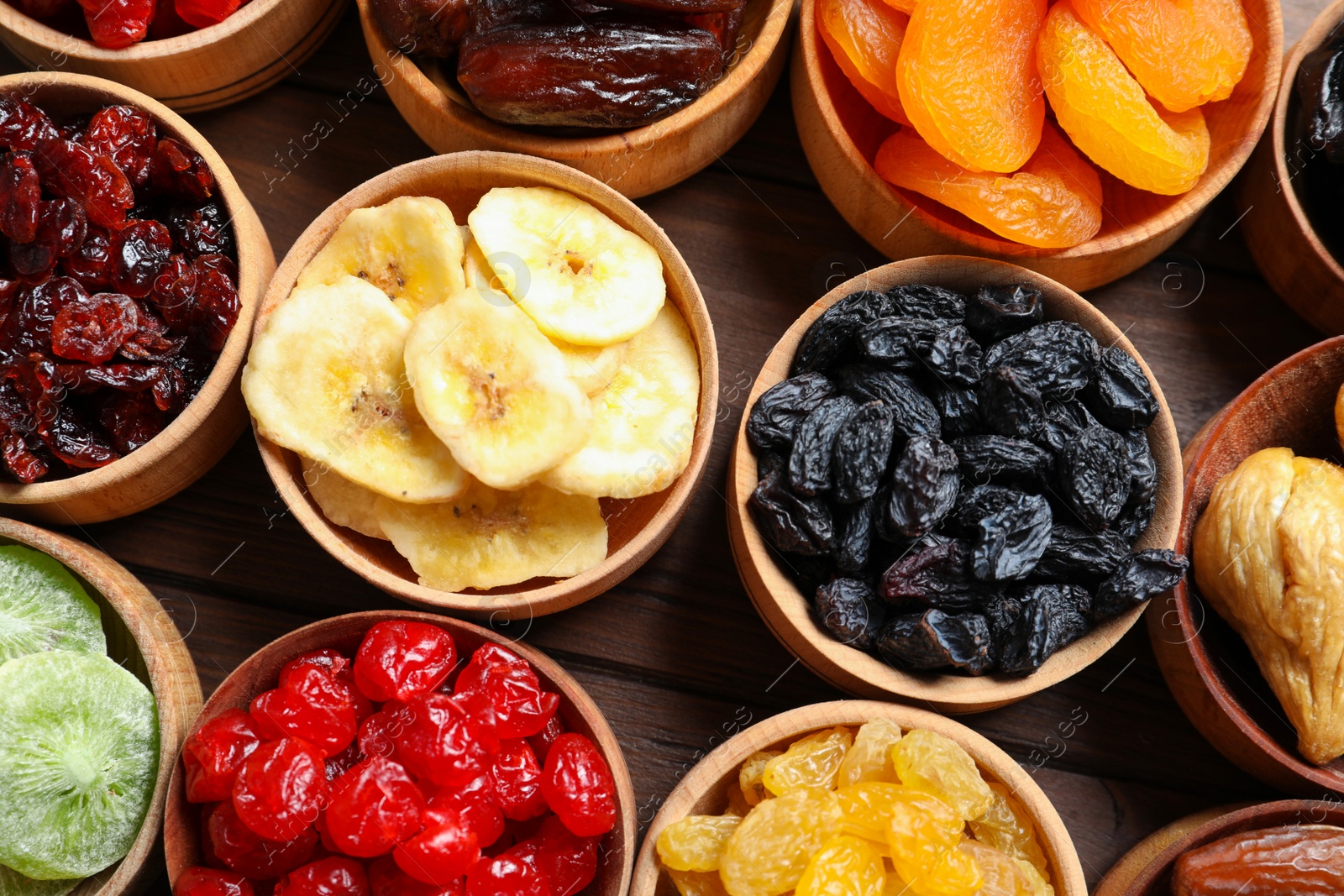 Photo of Bowls with different dried fruits on wooden background, flat lay. Healthy lifestyle