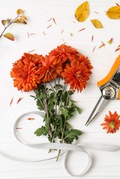 Flat lay composition with secateurs, ribbon and Chrysanthemum flowers on white wooden table