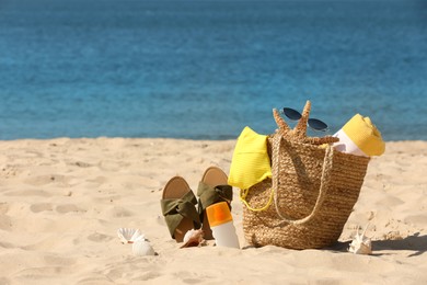 Bag with beach accessories and slippers on seaside. Space for text