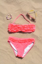Sunglasses and bikini on sand, flat lay. Beach accessories