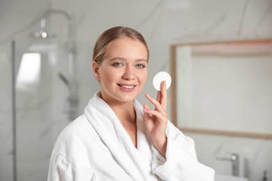 Beautiful young woman with cotton pad indoors