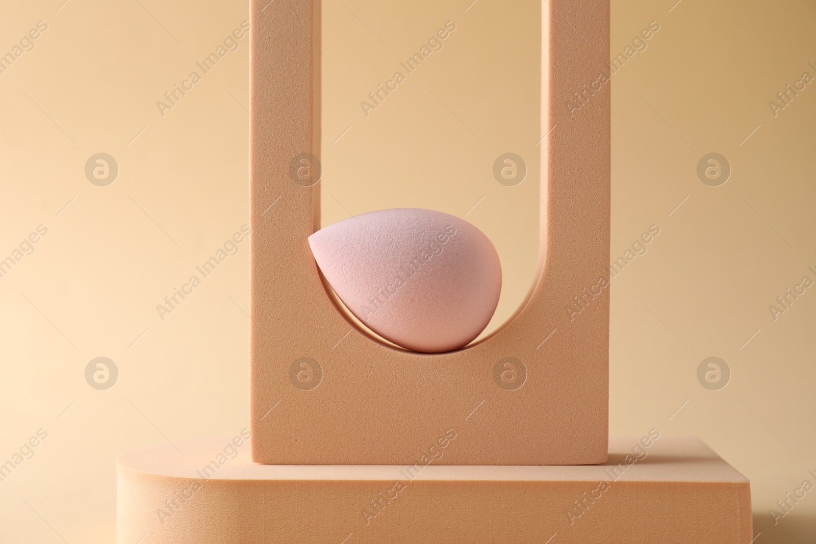 Photo of Stylish presentation of makeup sponge on beige background