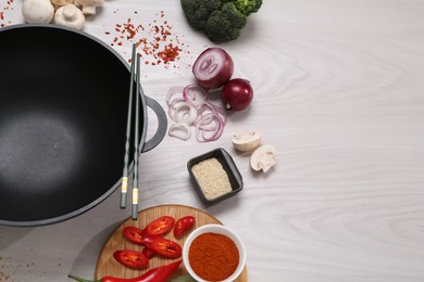 Photo of Wok, chopsticks and different products on white wooden table, above view. Space for text