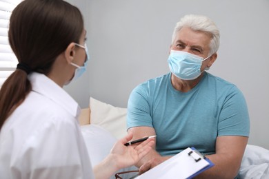 Photo of Doctor examining senior man with protective mask at nursing home