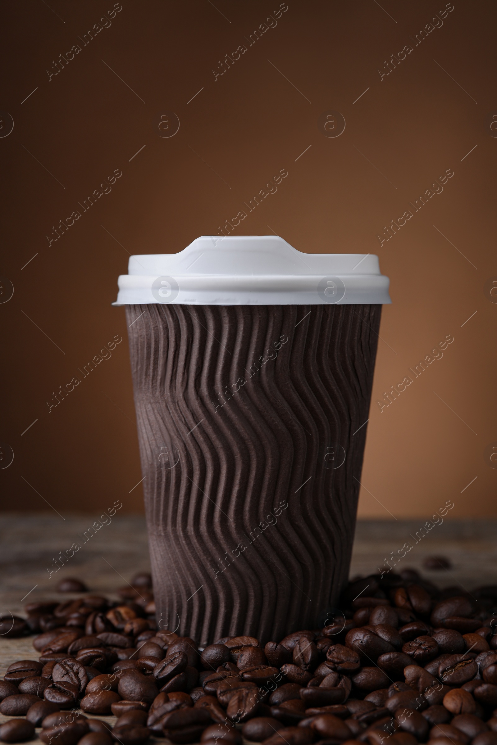 Photo of Coffee to go. Paper cup and roasted beans on table against brown background
