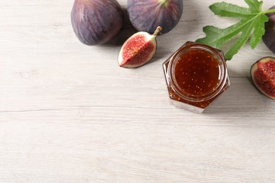 Jar of tasty sweet jam and fresh figs on white wooden table, flat lay. Space for text