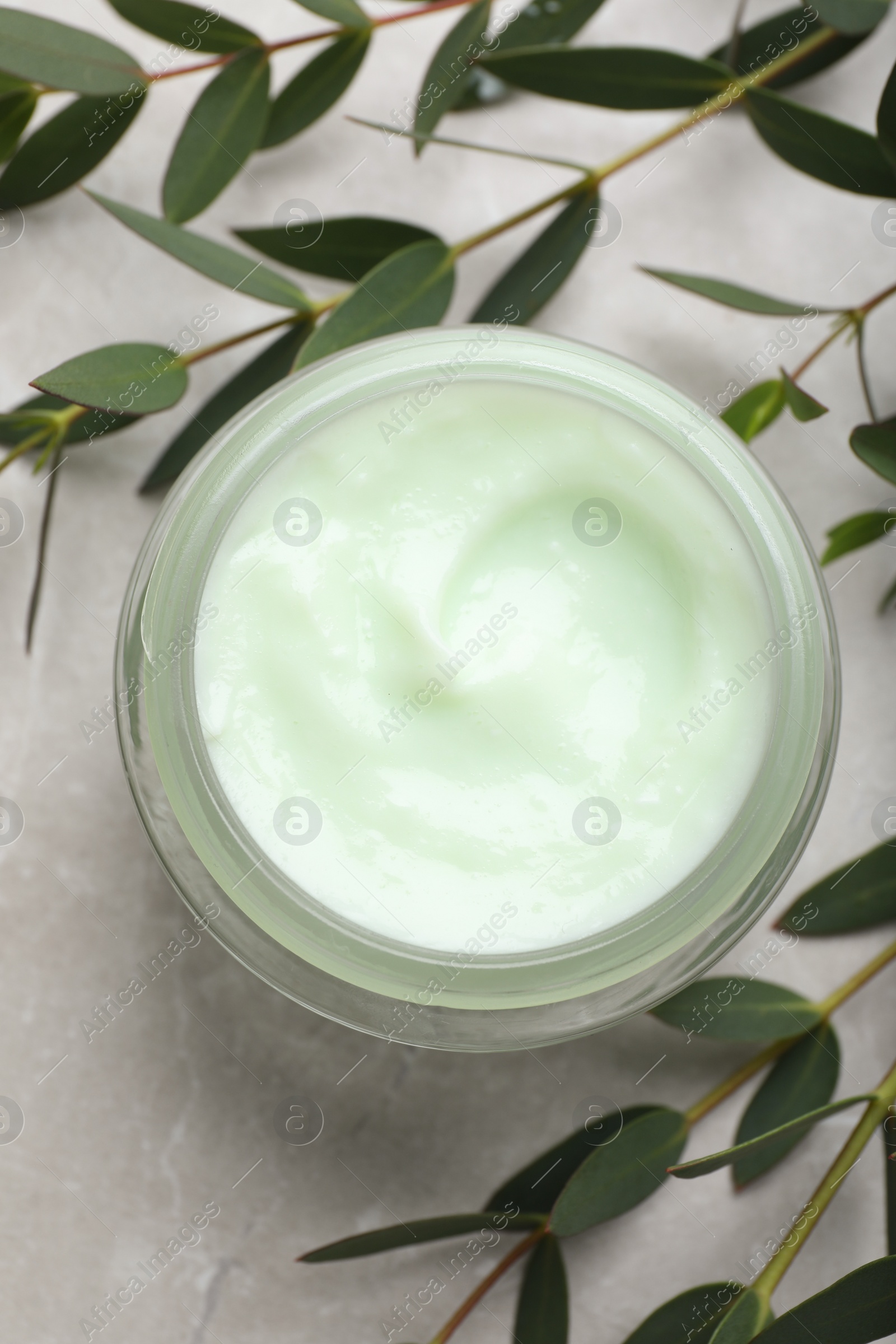 Photo of Jar of organic cream and eucalyptus on light marble table, flat lay