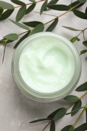 Photo of Jar of organic cream and eucalyptus on light marble table, flat lay