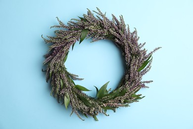 Beautiful heather wreath on light blue background, top view. Autumnal flowers