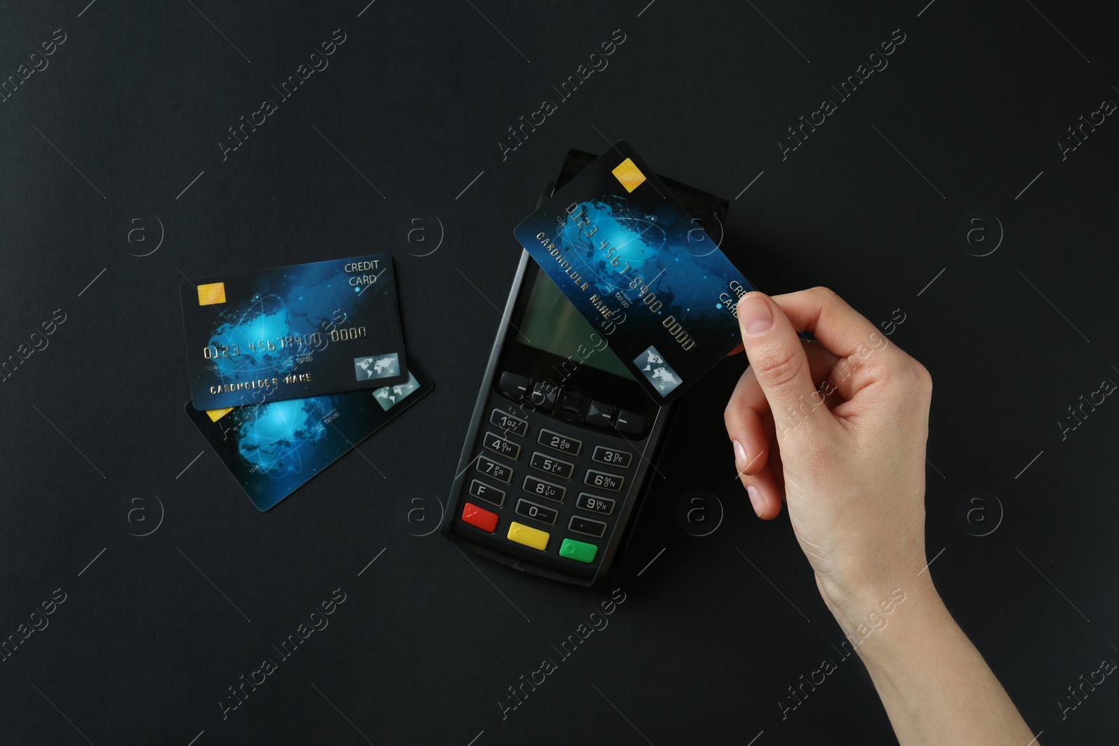 Photo of Woman with credit card using modern payment terminal on black background, top view