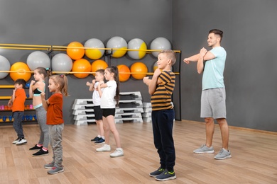 Cute little children and trainer doing physical exercise in school gym. Healthy lifestyle