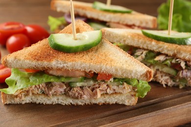 Photo of Delicious sandwiches with tuna and vegetables on wooden board, closeup