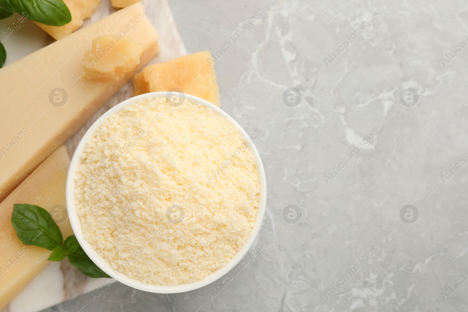 Photo of Flat lay composition with parmesan cheese and basil on grey table. Space for text