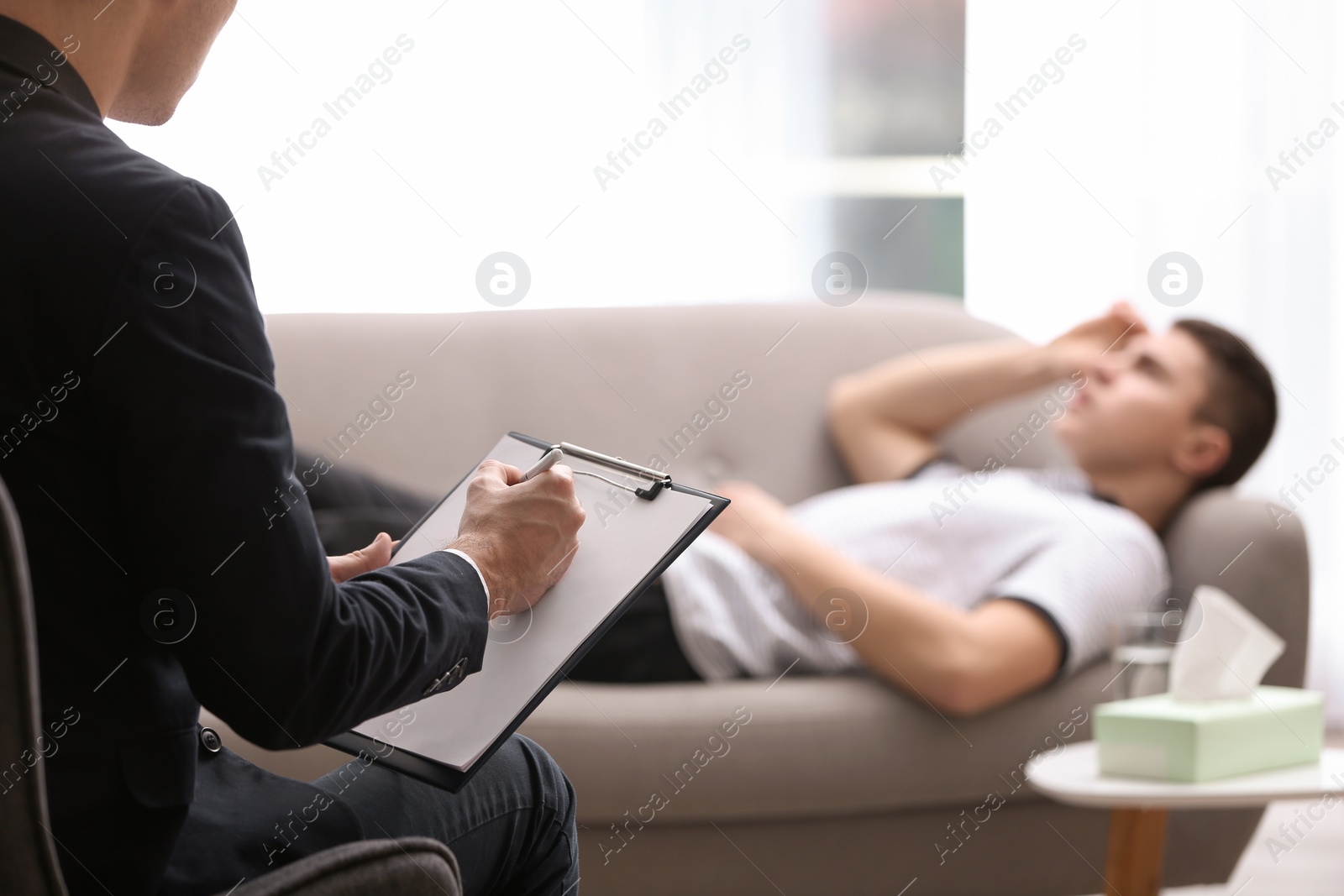 Photo of Psychotherapist working with young man in office, closeup