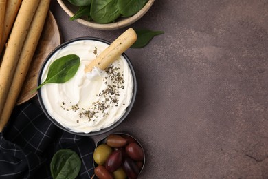 Delicious cream cheese with grissini stick, basil and olives on grey table, flat lay. Space for text