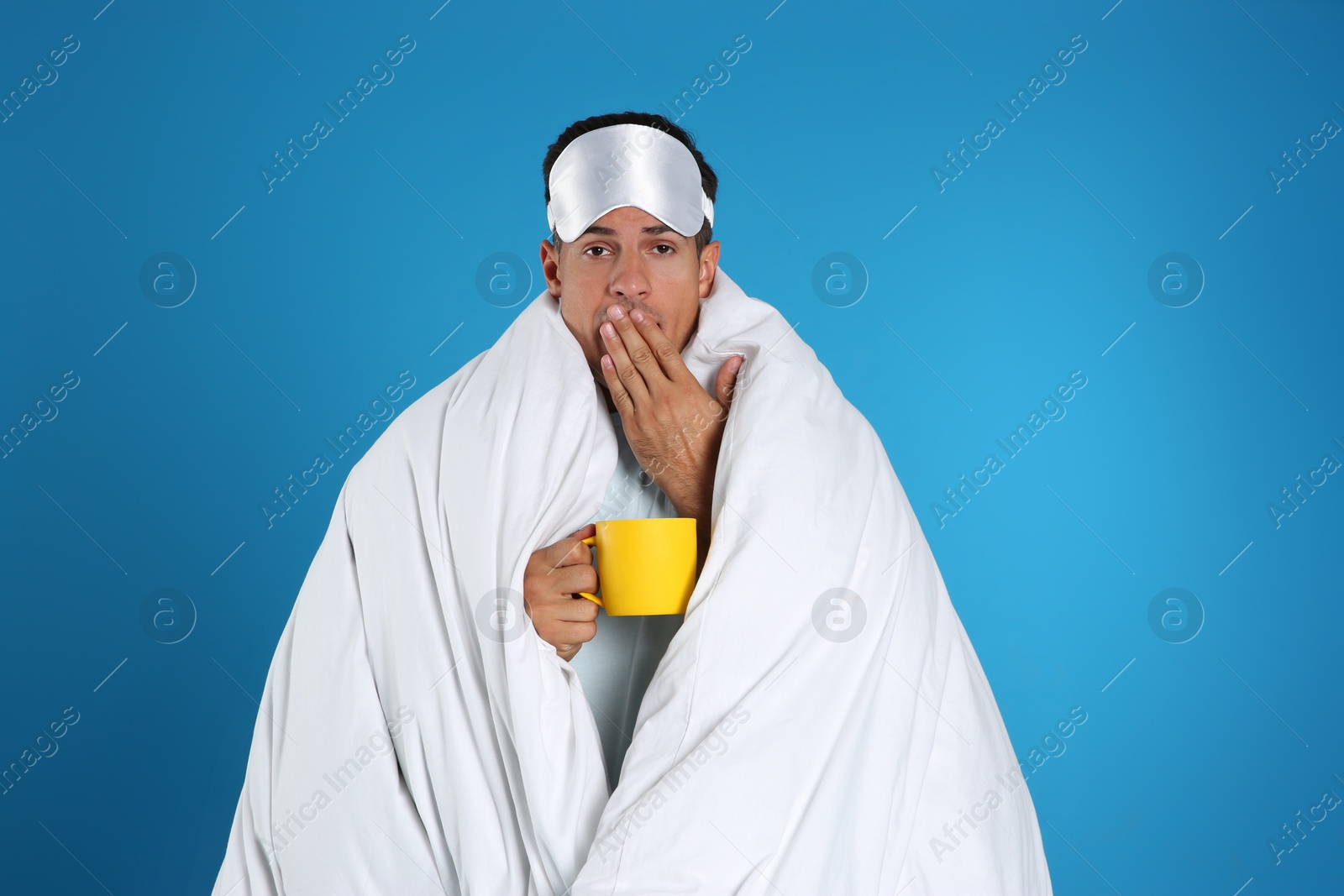 Photo of Man wrapped in blanket holding cup on blue background