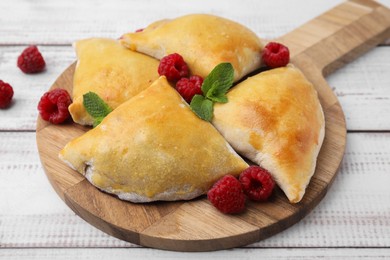 Delicious samosas with raspberries on white wooden table, closeup