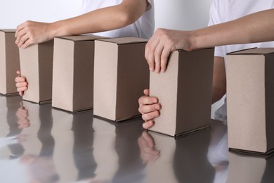 Photo of Workers folding cardboard boxes at table, closeup. Production line 