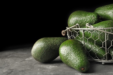 Photo of Delicious ripe avocados on grey table against dark background