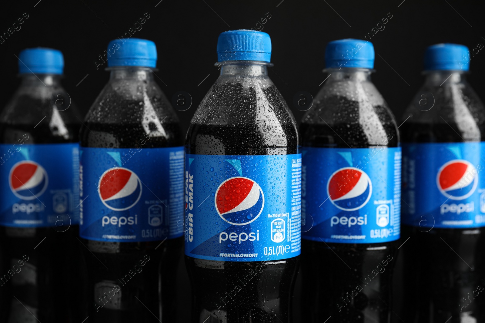 Photo of MYKOLAIV, UKRAINE - FEBRUARY 08, 2021: Plastic bottles of Pepsi with water drops on black background, closeup