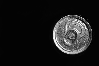 Aluminum can of beverage covered with water drops on black background, top view. Space for text