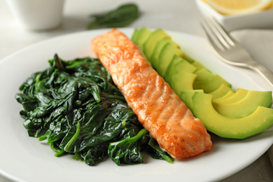 Photo of Tasty salmon with spinach and avocado on plate, closeup