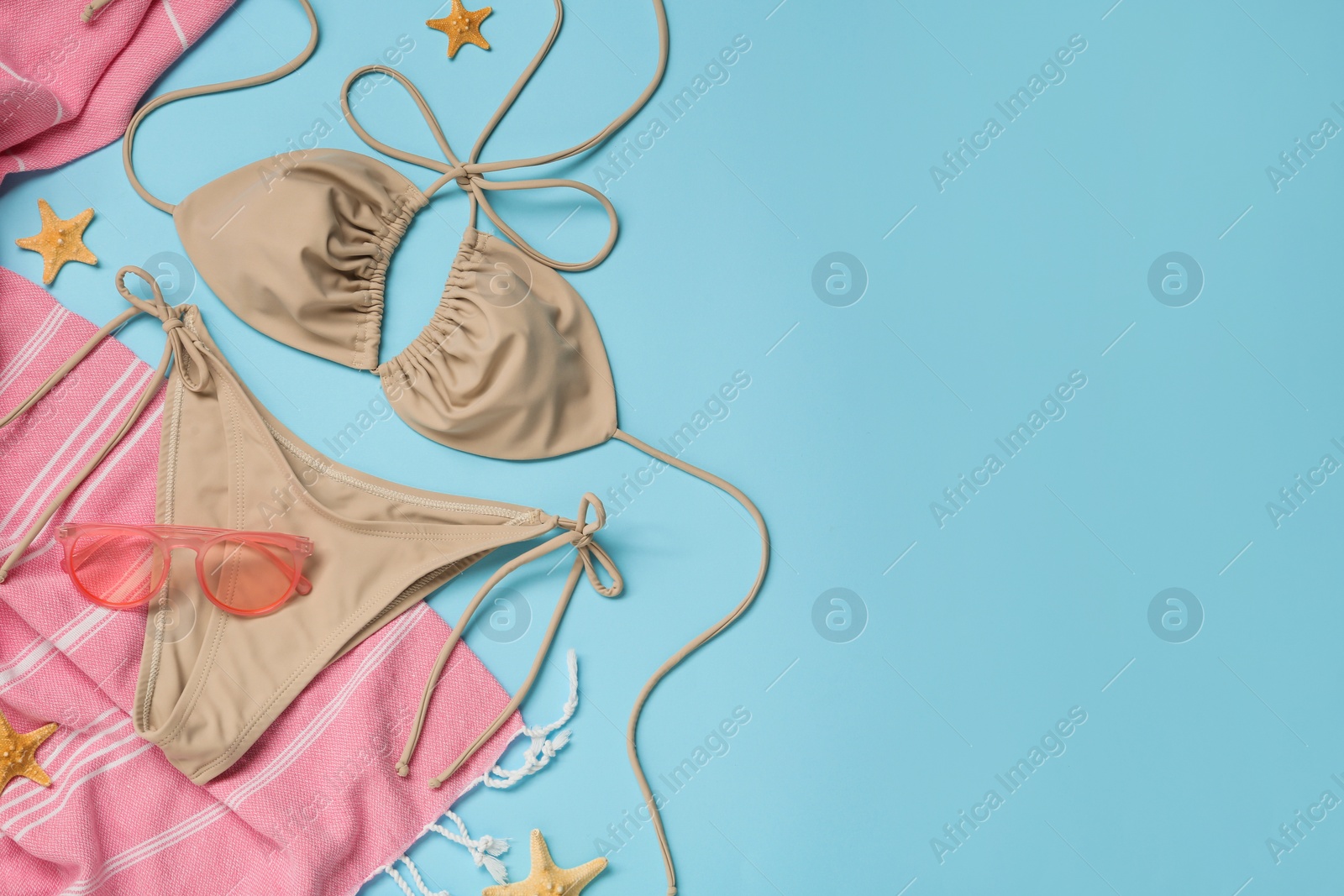 Photo of Stylish bikini and beach accessories on light blue background, flat lay. Space for text