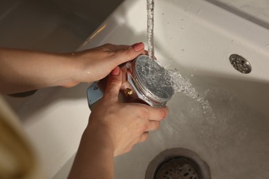 Photo of Woman washing moka pot at sink in kitchen, closeup