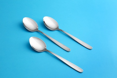 Photo of Clean empty table spoons on blue background