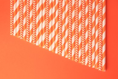 Many striped paper drinking straws on orange background, flat lay