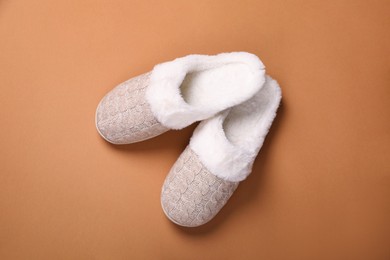 Photo of Pair of beautiful soft slippers on light brown background, top view