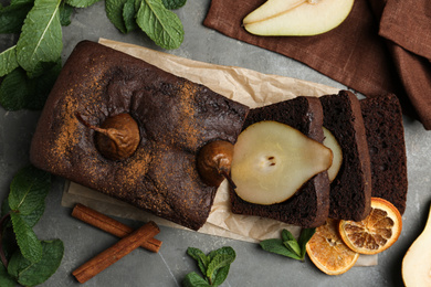 Photo of Tasty pear bread with cinnamon, mint and dried orange slices on grey table, flat lay. Homemade cake