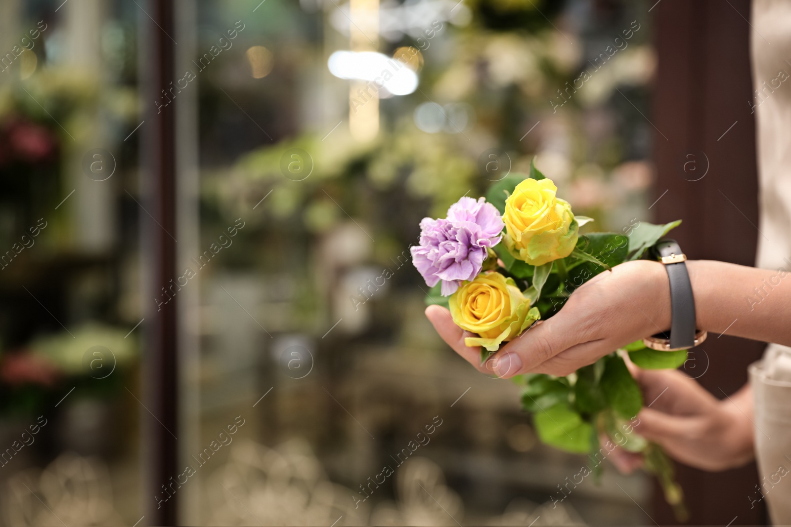 Photo of Female florist holding beautiful bouquet in flower shop, closeup