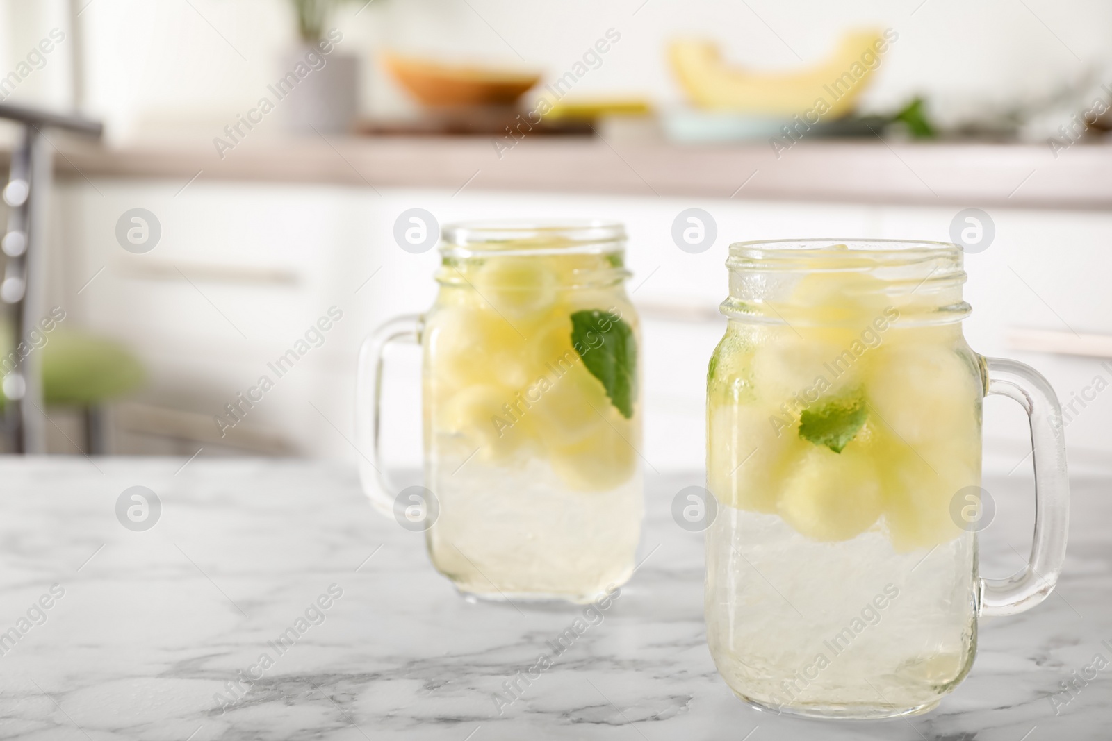 Photo of Tasty melon ball drink on white marble table indoors. Space for text