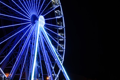 Photo of Beautiful glowing Ferris wheel against dark sky. Space for text
