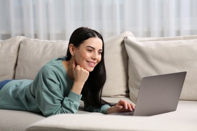 Happy woman working with laptop on sofa at home