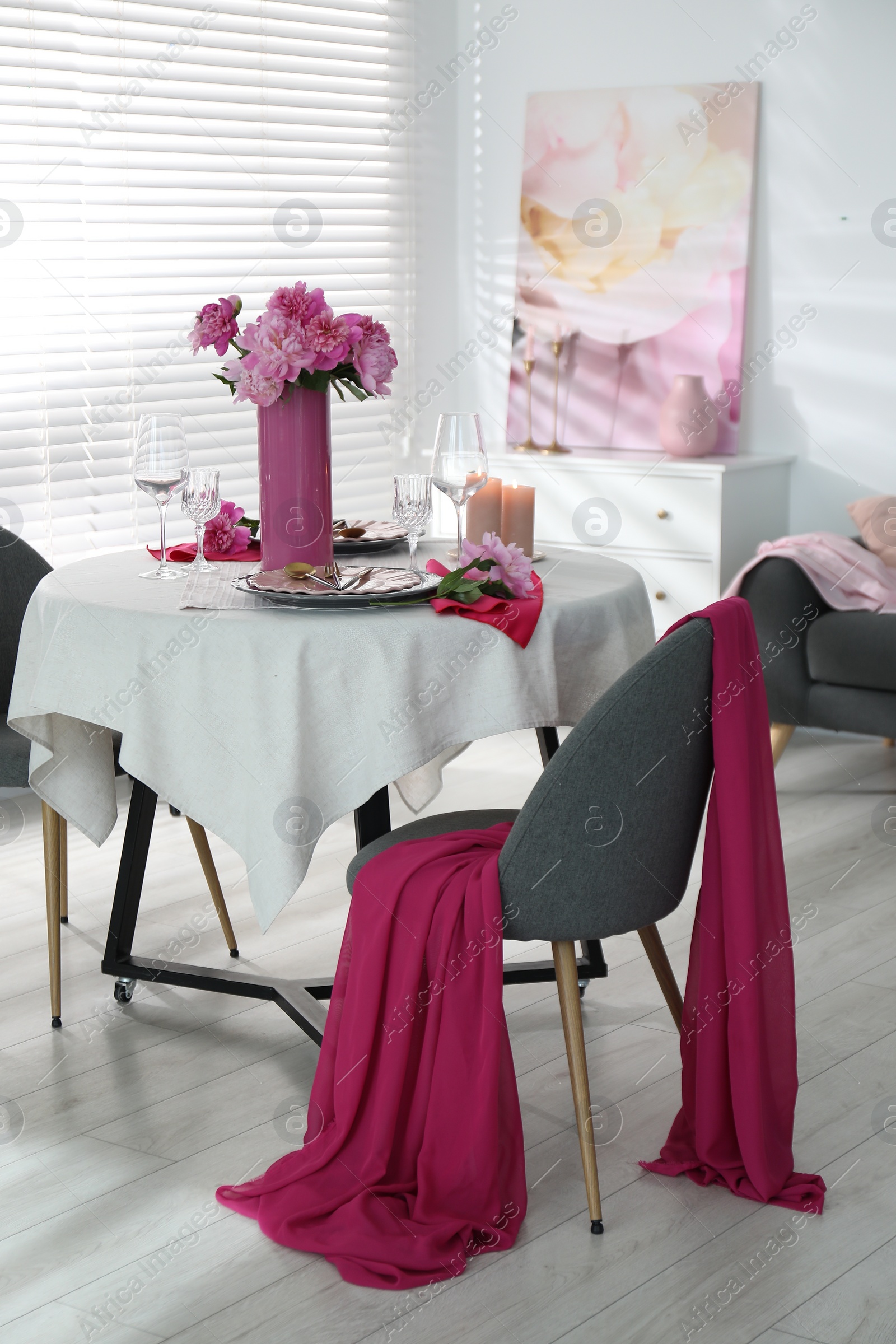 Photo of Pink peonies on table with beautiful setting and chair in dining room