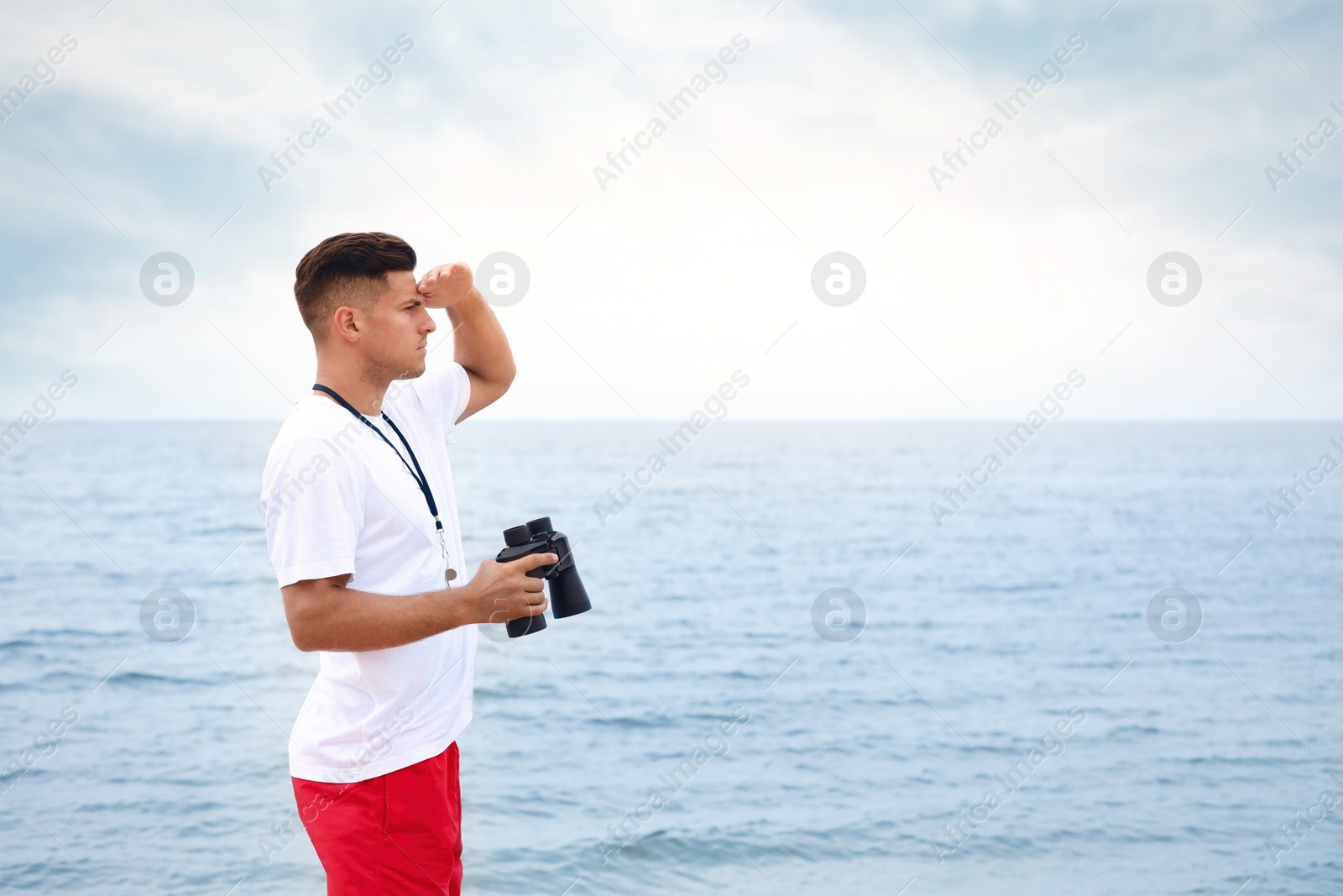 Photo of Handsome male lifeguard with binocular near sea