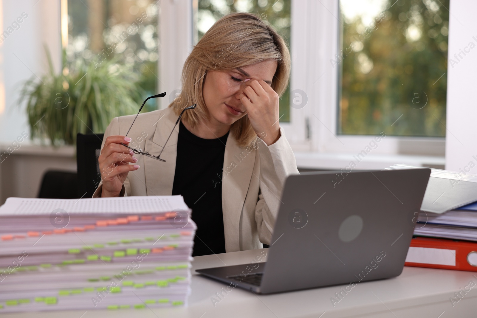 Photo of Overwhelmed woman sitting at table in office