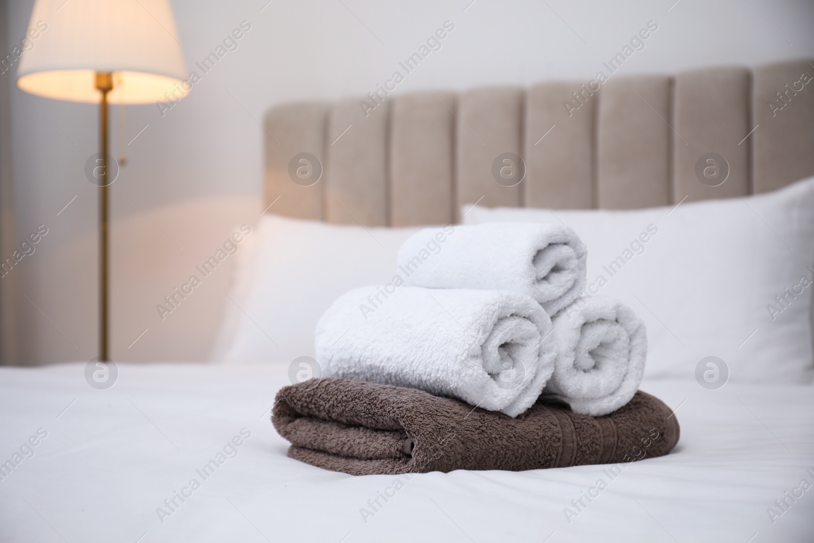 Photo of Soft clean towels on white bed indoors. Space for text