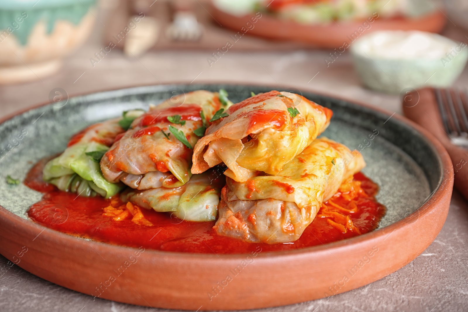 Photo of Plate with stuffed cabbage leaves in tomato sauce on table