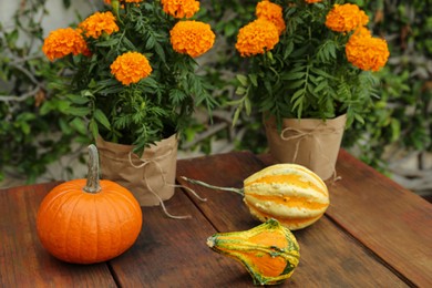 Fresh ripe pumpkins and flowers on wooden table outdoors