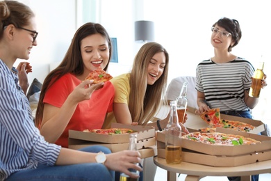 Young people having fun party with delicious pizza indoors