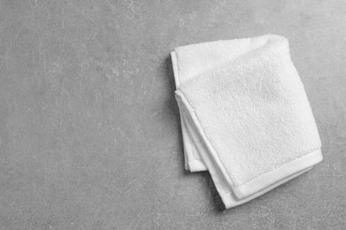 Photo of Soft folded towel on gray background, top view. Space for text